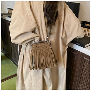 Detail of vintage brown suede crossbody bag featuring rivets and bohemian fringe tassels