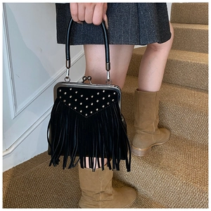 Detail of vintage black handbag with metal rivets, fringe tassels, and retro clasp lock