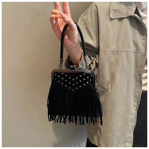 Close-up of black crossbody bag featuring gold rivets, long fringe, and vintage metal clasp