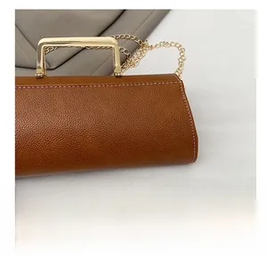 Detailed close-up of brown litchi grain leather texture and gold metal handle on handbag