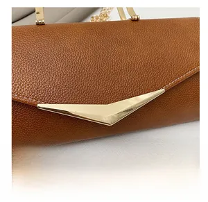 Detail view of brown lychee grain leather with golden V-shaped buckle and chain strap