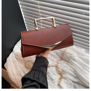 Detail of brown lychee leather handbag with gold V-metal decor and metal handle