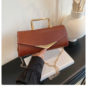 Detail of brown litchi pattern leather bag with gold V-clasp and metallic handle