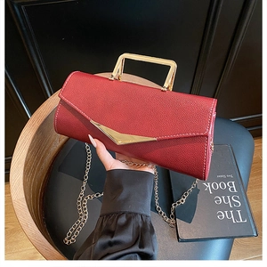 Close-up of burgundy lychee leather handbag with gold V-buckle and chain strap