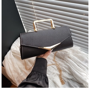 Detail of black crossbody bag featuring lychee texture leather and gold metal handle