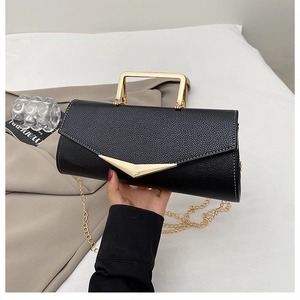 Detail view of black textured leather envelope bag with gold handle and chain strap