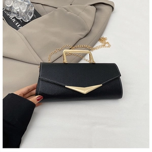 Detail of black pebbled leather handbag with gold metal handle and V-shaped metallic accent