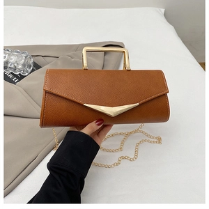 Detail of caramel leather envelope bag with gold metal handle and chain shoulder strap