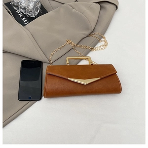 Close-up of brown litchi grain envelope bag with gold hardware on a beige blazer