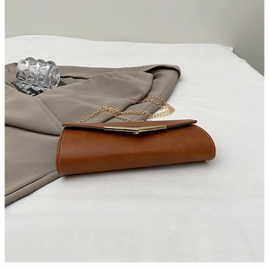 Detail of caramel lychee grain envelope bag with gold V-metal buckle and chain strap