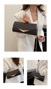 Detail of black envelope handbag with gold U-shaped handle and V-shaped metal buckle