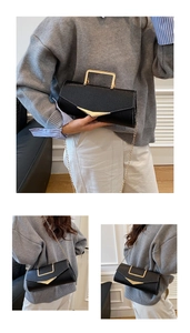 Close-up of black lychee leather crossbody bag with V-shaped gold hardware and chain strap