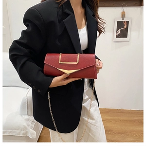Deep red envelope bag with gold V-hardware and chain strap shown with fashion outfit