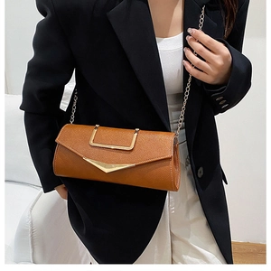 Brown litchi grain leather shoulder bag with golden V-shaped buckle on black suit jacket