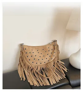 Détail d'un sac besace en daim marron avec œillets métalliques et longues franges bohèmes