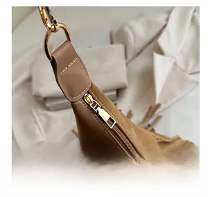 Detail of smooth metal zipper and brown suede stitching on the tassel tote bag