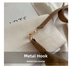 Detailed close-up of golden metal lobster clasp on a brown suede crossbody bag strap