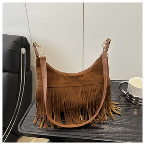Close-up of brown suede shoulder bag featuring long fringe tassels and gold hardware hooks