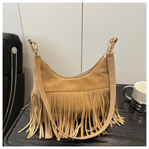 Detail of tan suede shoulder bag featuring long fringe texture and zipper closure