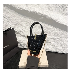Close-up of black crocodile pattern mini bag with gold chain and round top handle