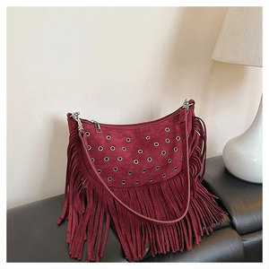 Détail du sac besace bordeaux en daim avec œillets argentés et longues franges style