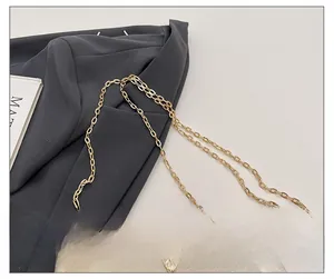 Detailed macro view of the champagne gold chain strap and feather shaped buckle on handbag