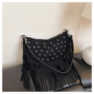 Détail du sac bandoulière à franges noires avec œillets métalliques et texture suédée