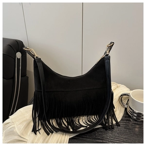 Detail of a black bohemian crossbody bag featuring long fringes and gold metal hardware