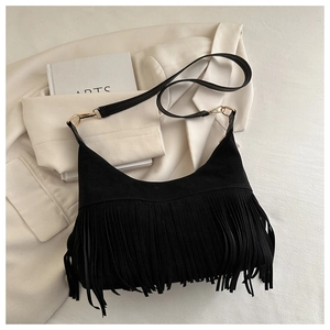 Detailed macro view of black suede fringed bag showing dense tassels and gold hardware