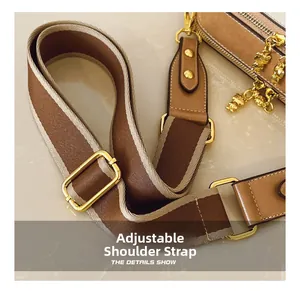 Detail of adjustable striped strap with gold hardware and bear charm on small bag