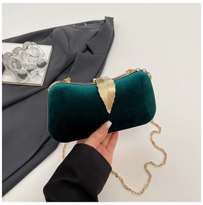 Detail of dark green velvet evening bag with gold leaf clasp and metal chain strap