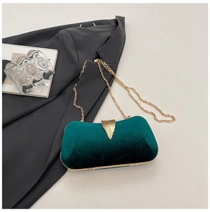 Detail of dark green velvet evening clutch bag with gold leaf clasp and metal chain strap