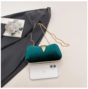 Detail of emerald velvet evening bag with golden leaf buckle and chain strap