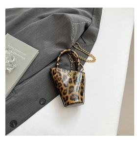 Detailed close-up of mini leopard print bucket bag with gold chain on grey blazer