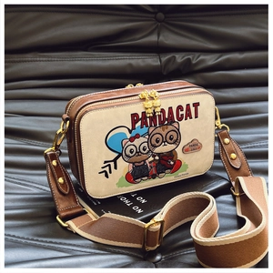 Close-up of a bear cartoon square crossbody bag with dual gold zippers and striped strap
