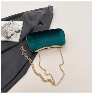 Detail of dark green velvet clutch with gold metal chain and spherical clasp closure