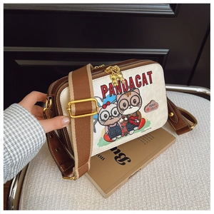 Detail of Panda Cat canvas bag showing golden cat charm and adjustable brown strap