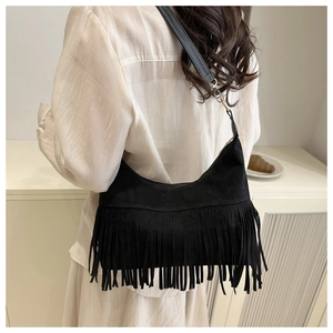 Detail of black suede tassel shoulder bag showing the fringe texture and strap on a model