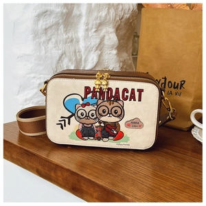Detail of cartoon cat embroidery and double zippers on the beige crossbody bag