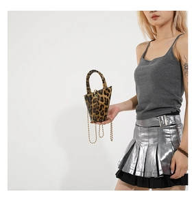Detailed shot of a mini leopard print bucket bag featuring a sleek gold chain shoulder strap