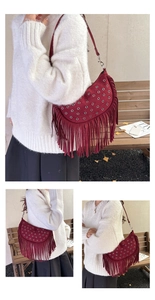 Détail du sac selle en daim bordeaux avec œillets métalliques et longues franges