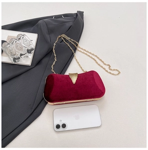 Detail view of burgundy velvet evening clutch bag with golden leaf clasp and chain strap