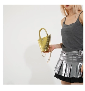 Macro detail of golden crocodile embossed mini bucket bag with metallic ball chain