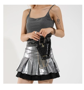 Detail of glossy black crocodile embossed bucket bag with gold chain and metal accents