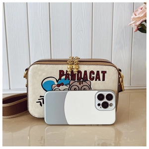 Detail of cartoon cat embroidery on cream crossbody bag with phone for size reference