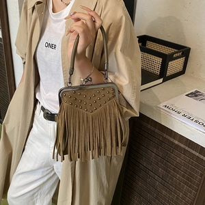 Vintage brown suede handbag with metal rivets and long tassels in a lifestyle setting