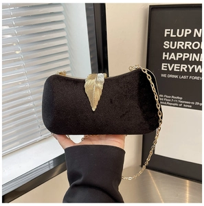 Detail of elegant black velvet evening clutch featuring a gold leaf clasp and chain strap