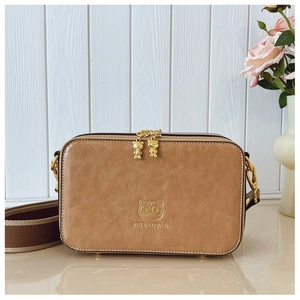 Detail of camera bag featuring golden bear zipper charms and striped woven strap