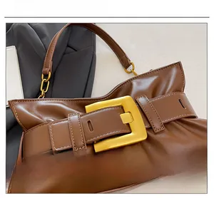 Close-up of retro brown leather bag with large gold square buckle and chain detail