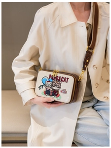 Detail of crossbody bag with panda cat print and brown fabric strap on beige coat